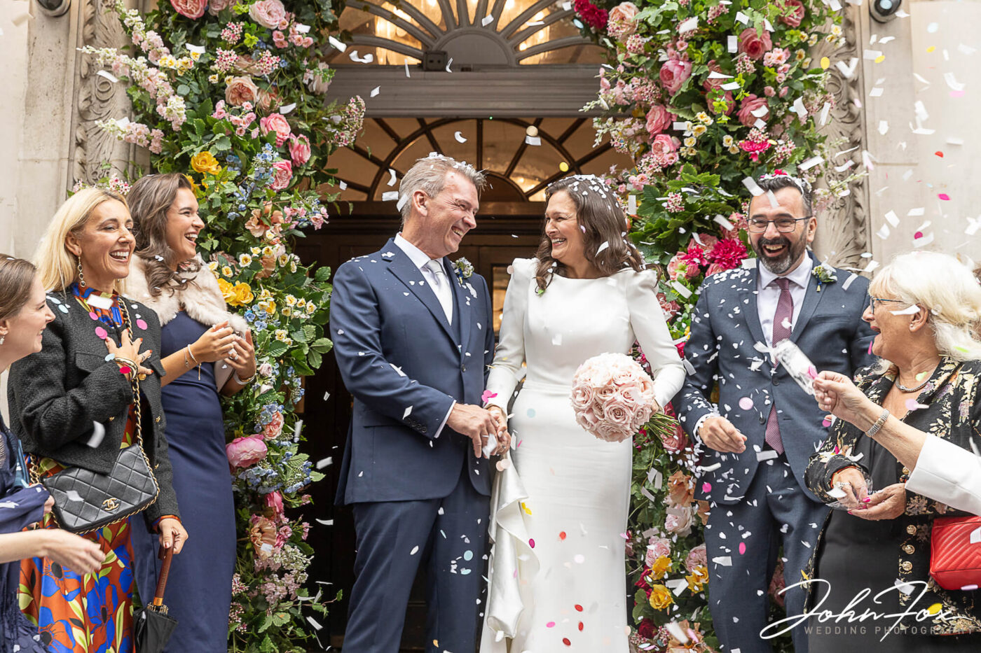 Amanda and Alex outside Chelsea Registry Office and being showered with confetti by their wedding guests.