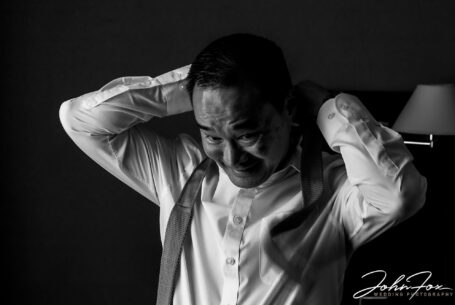 Son the groom preparing for his wedding; image of him putting his tie on. Hadley Park House Wedding Photography