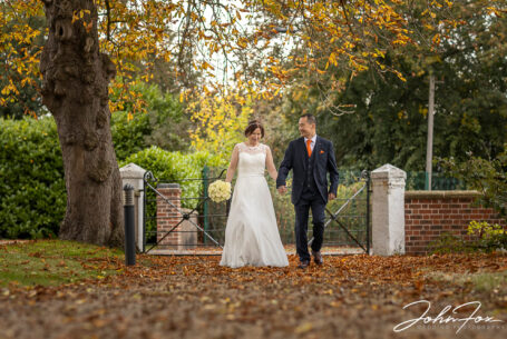 Bride and groom walking in an autumnal setting at Hadley Park House.