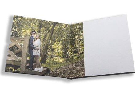 Sophie and Jack's guest book displaying an image of them by a wooden bridge at Hothorpe Hall The Woodlands.