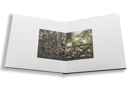 Sophie and Jack's guest book with an image of the bride and groom-to-be on a wooden bridge at Hothorpe Hall The Woodlands