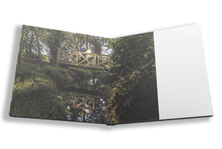 Sophie and Jack on the wooden bridge with their reflection in a stream at Hothorpe Hall The Woodlands. Photo by John Fox Wedding Photography