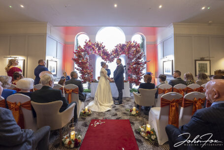 The wedding ceremony taking place in front of elegant arched windows at the Holiday Inn East in Milton Keynes