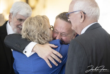 Matthew the groom getting hugs from guests after the ceremony at Holiday Inn East in Milton Keynes. Image by John Fox Wedding Photography.