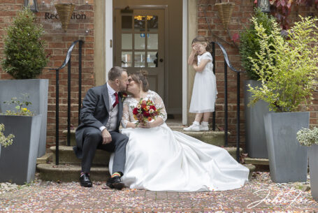 The newly-weds sharing a kiss on the steps at the Holiday Inn East in Milton Keynes with their daughter covering her eyes