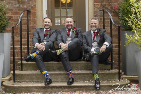 Groom and groomsmen showing their socks by croosing their legs while sat on the steps at the Holiday Inn East in Milton Keynes.