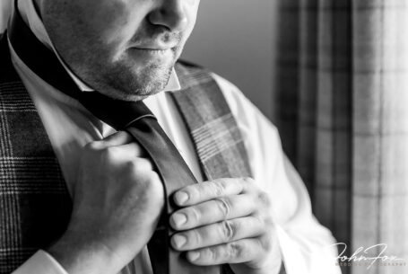 James, the groom, tying his tie. Wedding Photography at The Ashes Barns in Staffordshire