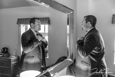 James the groom looking in a mirror while getting ready for his wedding at The Ashes Barns in Staffordshire