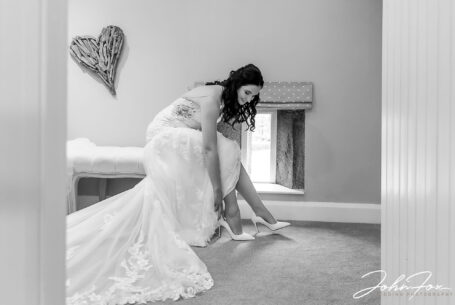 Bride putting on her wedding shoes. Photo by John Fox Wedding Photography