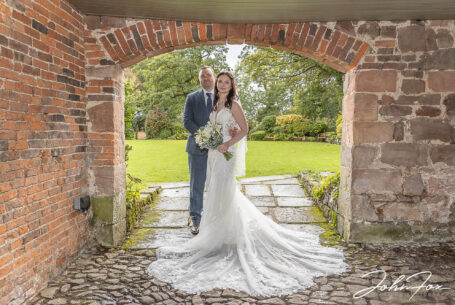 Bride and groom portrait framed by a brickwork arch