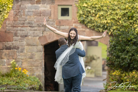 Groom carrying the bride as she's laughing. Photo by John Fox Wedding Photography