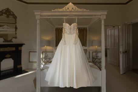 Wedding dress hanging on a four poster bed. Cambridgeshire wedding photography by John Fox.