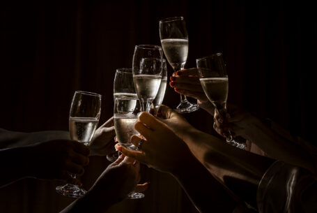 Champagne celebration: 5 glasses of bubbly being held aloft. Image by John Fox Wedding Photography