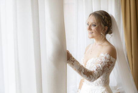 Tanya the Bride in her wedding dress looking out of a window at Holmewood Hall