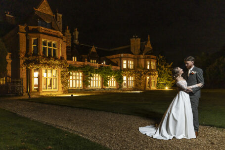 Night time wedding photograph of Tanya and Shane with a floodlit Holmewood Hall in the background