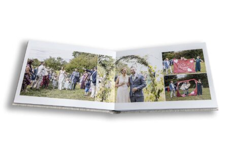 Wedding album open showing the design of images from Charlotte and Stefan's wedding at the Tractor Barn in Northamptonshire. Photos by John Fox Wedding Photography