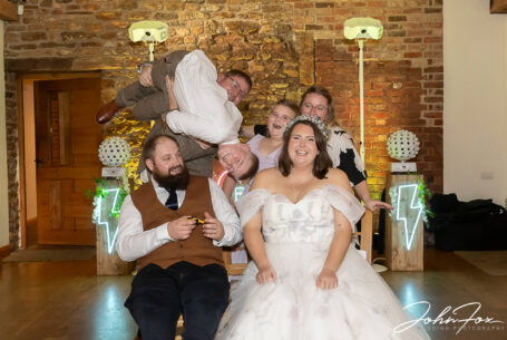 One of the wedding guests being held upside down over the bride and groom on Abigail and Daniel’s special day at Dodford Manor