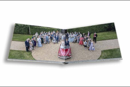 An aerial shot taken by John Fox's drone of the wedded couple sat in a vintage sports car surrounded by their wedding guests.