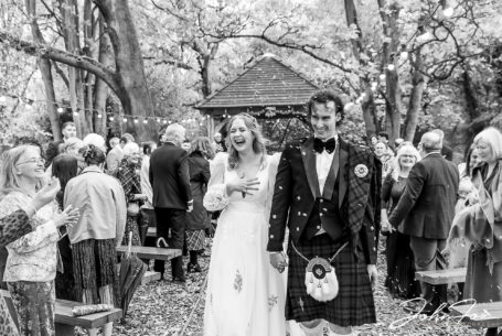 The newly-weds being showered in confetti at their wedding at Hothorpe Hall, Northamptonshire. Black and white image by John Fox Wedding Photography