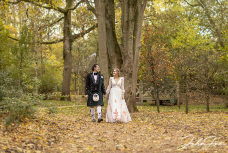 Bride and groom walking in a woodland setting at Hothorpe Hall, Northamptonshire