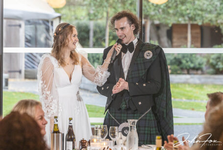 Jack makes his wedding speech while Sophie holds the mic at their Hothorpe Hall wedding in Northamptonshire