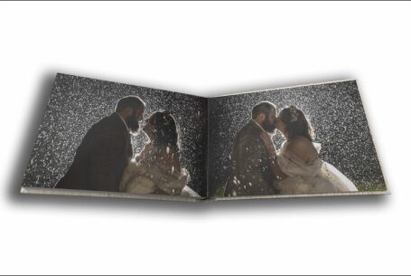 Abigail and Daniel’s Dodford Manor Wedding Album opened at pages showing images of the bride and groom kissing in the evening rain