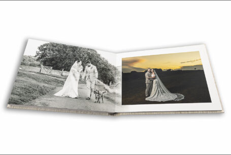 Wedding album open showing bride and groom in the grounds at Kingscote Barn