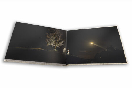 Wedding album open showing an image of Gabrielle and William at Kingscote barn with the stars and moon above