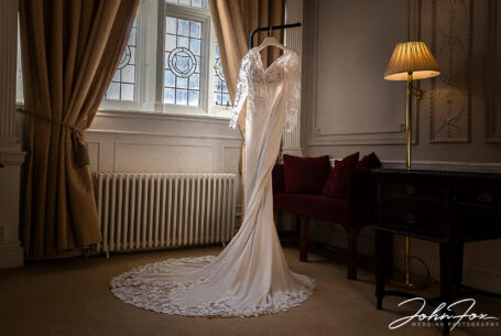 Joanne's wedding dress hanging up at a suite at Rushton Hall. Wedding packages in Northamptonshire