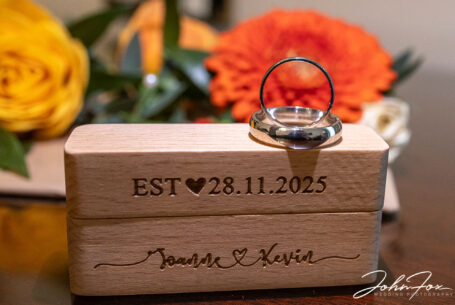 Wedding rings with a flower arrangement in the background. Wedding packages in Northamptonshire