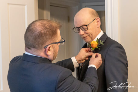 Groom and best man getting ready. Kevin helping the best man with a flower added to his jacket. Wedding packages in Northamptonshire