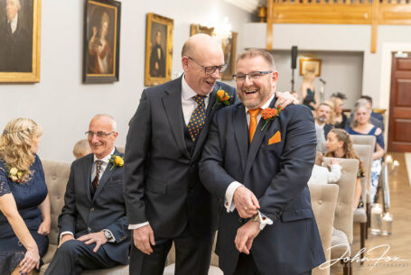 Groom and best man sharing a joke before the ceremony at Rushton Hall. Wedding packages in Northamptonshire