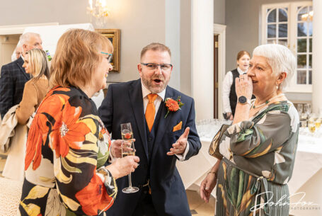Kevin, the groom, chatting with guests at his wedding celebrations at Rushton Hall in Northamptonshire