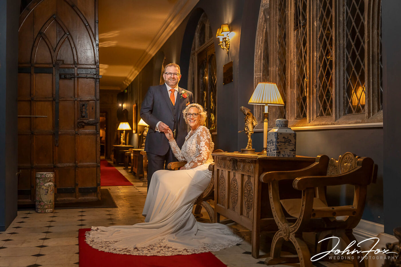 Newly-weds Joanne and Kevin in a hallway at Rushton Hall. Wedding packages in Northamptonshire from John Fox Wedding Photography.