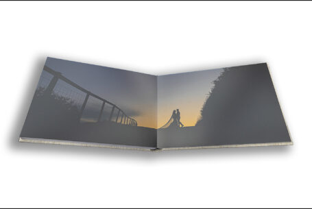 Exclusive Wedding Album opened at an image of Gabrielle and William silhouetted by sunset at Kingscote Barn in the Cotswolds.