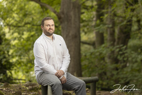 Pre-Wedding Shoot in Staffordshire at Rudyard Lake. Image of James, the groom-to-be sitting on a low wooden fence