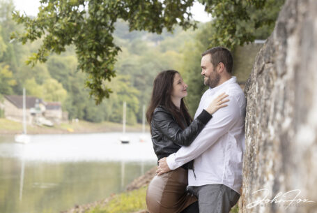 Pre-Wedding Shoot in Staffordshire at Rudyard Lake. Joanne and James leaning against a stone wall with the lake in the background