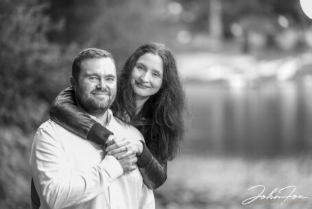 Pre-Wedding Shoot in Staffordshire at Rudyard Lake. Joanne with her arms around James and the lake slightly blurred in the background.