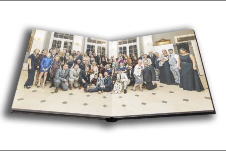 Wedding album opened at a page showing Joanne and Kevin with all of their wedding guests at Rushton Hall, Northamptonshire.