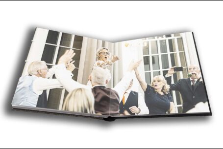 Wedding album opened at a page showing Joanne the bride celebrating with guests at her Rushton Hall wedding, Northamptonshire.