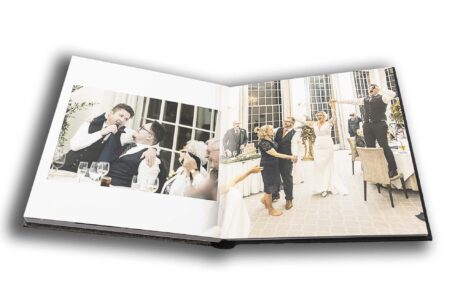 Wedding album opened at a page showing a singing waiter with his arm around Kevin the groom at Rushton Hall, Northamptonshire.