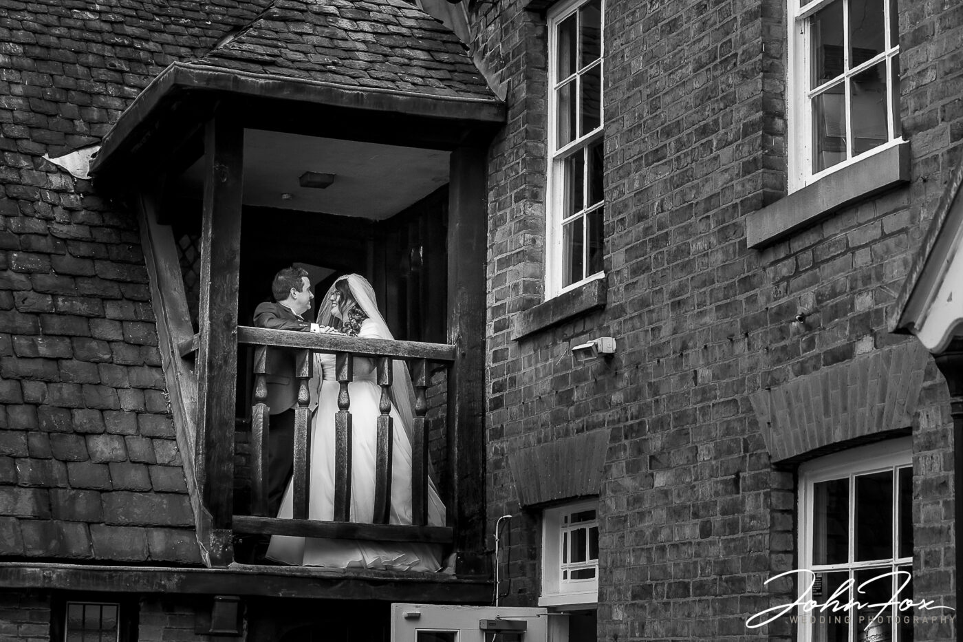 Amy and Karl on a balcony at Wygston House. Wedding Photography in Leicestershire from John Fox.