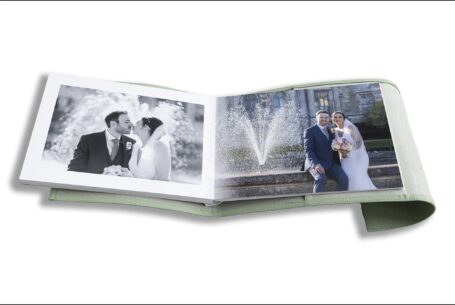 Nicole and Nicholas’s Wedding Album opened at pages showing images of of the newly-weds kissing by a fountain at Ashridge House