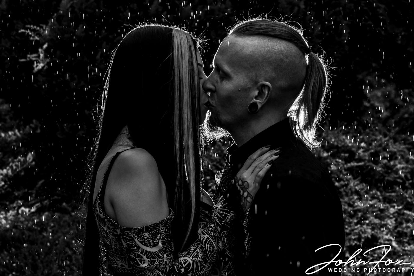 Louise and Jason, the bride and groom-to-be, sharing a kiss in the rain at Moreteyne Manor in Bedfordshire. Professional wedding photographer in Bedfordshire