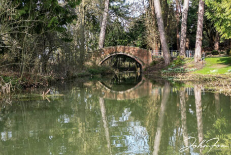 The bridge that crosses the lake at Brownsover Hall in Warwickshire with the trees reflected in the water. John Fox Wedding Photography.