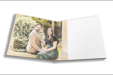 Elly and Olly’s pre-wedding shoot guest book opened at an image of the couple sitting on a stone bench at Kilworth House in Leicestershire