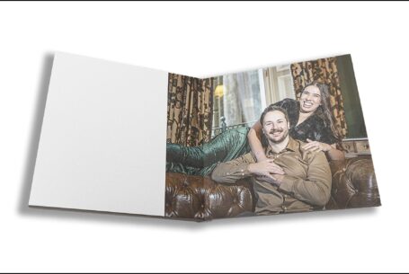 Elly and Olly’s pre-wedding shoot guest book opened at an image of the couple-to-be lounging on a leather sofa at Kilworth House in Leicestershire