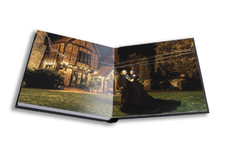 Wedding album open at an image of Louise and Jason in the grounds at Moreteyne Manor on the evening of their wedding day with the splendid venue in the background.