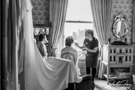 Eleanor's bridal preparations at Kilworth House in Leicester. The bride having her make-up applied while sitting at a window,