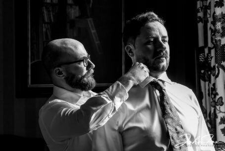 Image by John Fox Wedding Photography of Oliver being helped with his tie by one of the groomsmen. Wedding Photographer at Kilworth House in Leicester